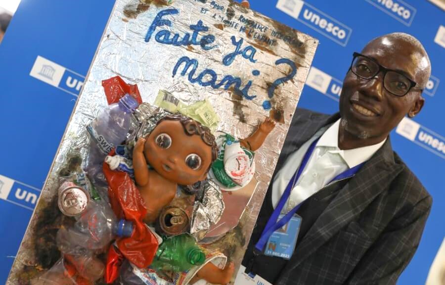 Adolphe Tungilu Luwana, Office for the Integrated Growth and Dignity of the Child (BCIDE), holds a piece of art from plastic waste, made by children in the Democratic Republic of the Congo, that asks 'whose fault is this?' Adolphe Tungilu Luwana, Office for the Integrated Growth and Dignity of the Child (BCIDE), holds a piece of art from plastic waste, made by children in the Democratic Republic of the Congo, that asks 'whose fault is this?'